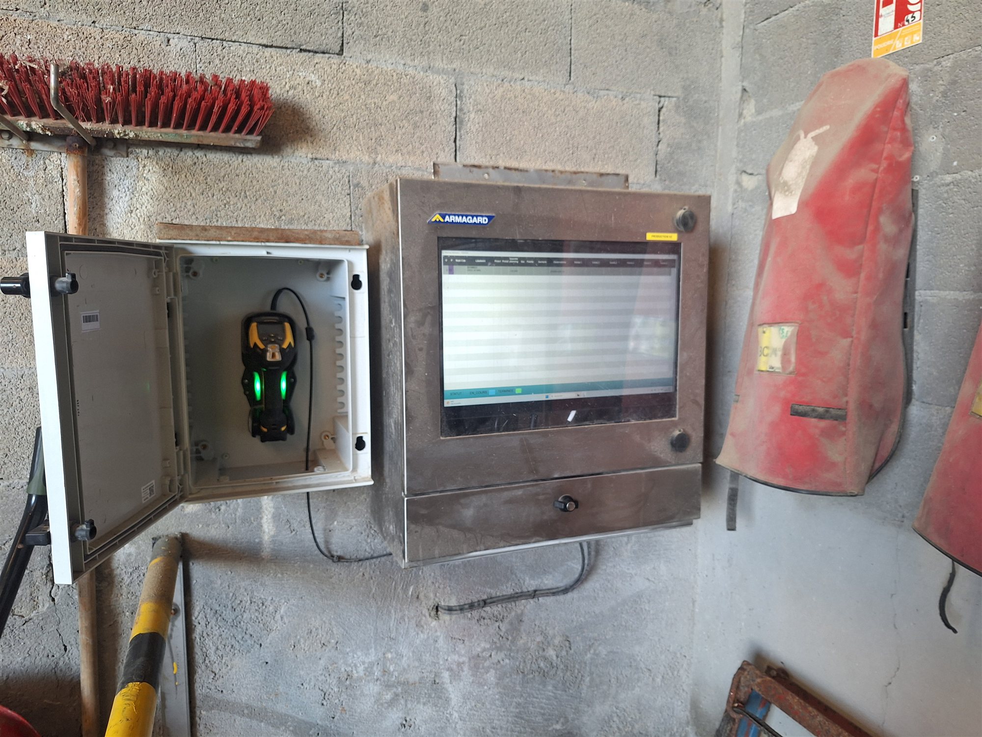 Écran et scanette fixés au mur de l'atelier : les saisies se font directement sur le poste, sans papier